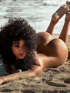 sexy black woman lying down nude at beach with perfect ass in the air, feet up, arm stretched in front, cute afro