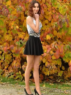 sexy leggy brunette posing in a park wearing short black mini skirt and nice clevy shirt